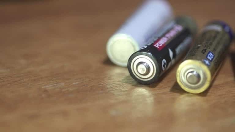 Close-up of AA batteries on wooden surface showing polarity