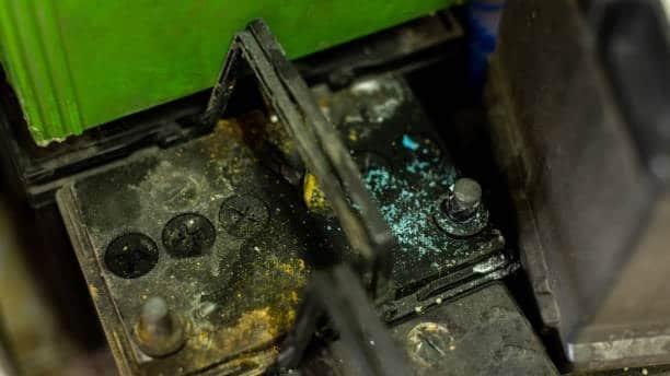Battery terminal with blue and yellow corrosion caused by acid leaks
