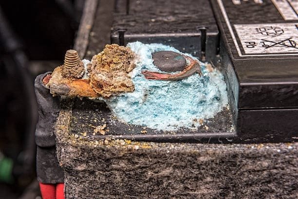 Heavy blue corrosion caused by battery acid leakage on a car battery