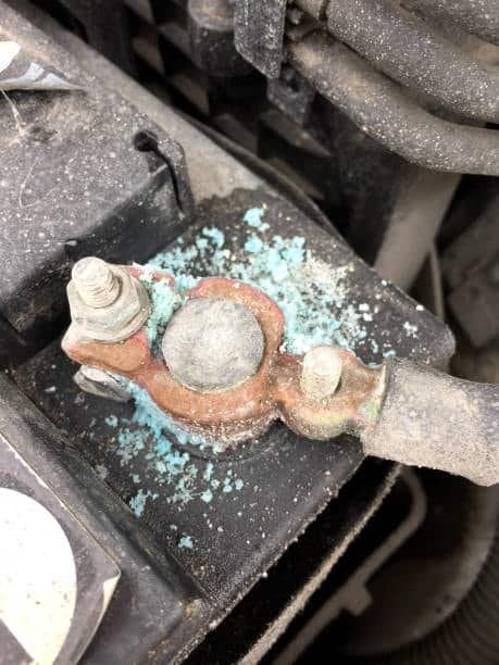 Close-up of blue powdery corrosion buildup on a car battery terminal