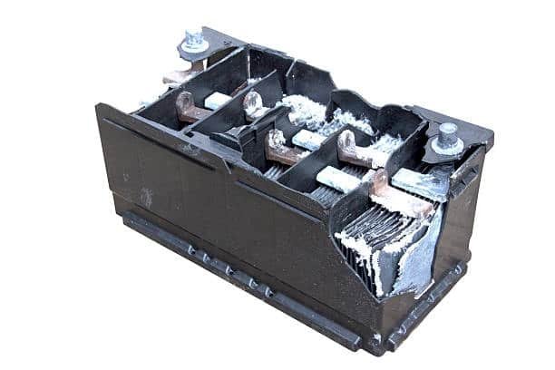 Broken car battery showing internal plates and severe acid corrosion