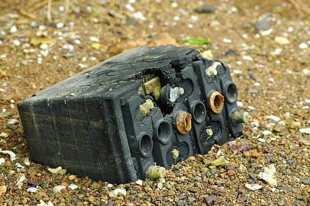 Broken and severely damaged car battery left on the ground