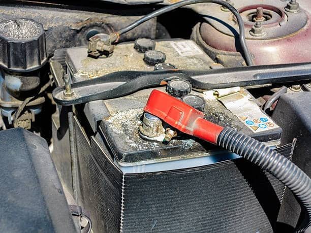 Car battery showing dust, dirt, and early-stage corrosion buildup on the terminal