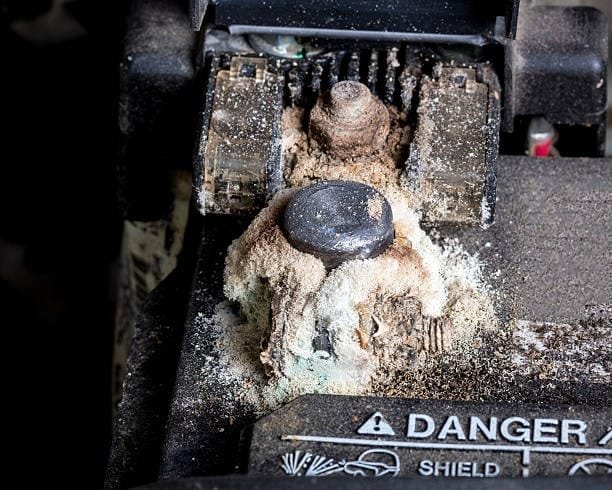 Severe corrosion buildup covering car battery terminal requiring immediate cleaning
