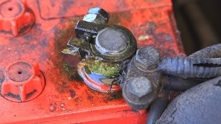 Severe green corrosion buildup on a dirty car battery terminal
