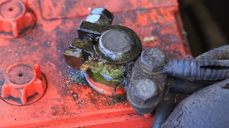 Severe green corrosion buildup around a leaking car battery terminal