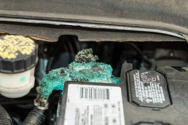 Thick green corrosion buildup covering a car battery terminal and connector