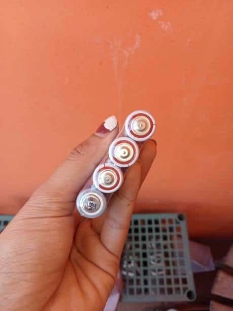 Hand holding four AA batteries arranged to build 12V power supply