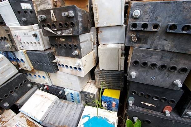 Pile of old used car batteries showing wear and acid stains