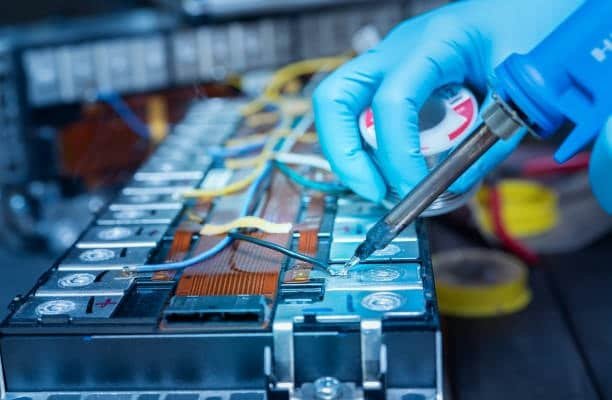 Technician repairing a lithium-ion battery pack using protective gloves and tools