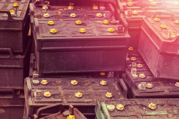 Stack of used car batteries showing risk of acid leakage over time