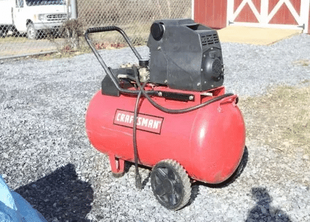Red Craftsman air compressor on wheels placed outdoors, suitable for garage and home projects.