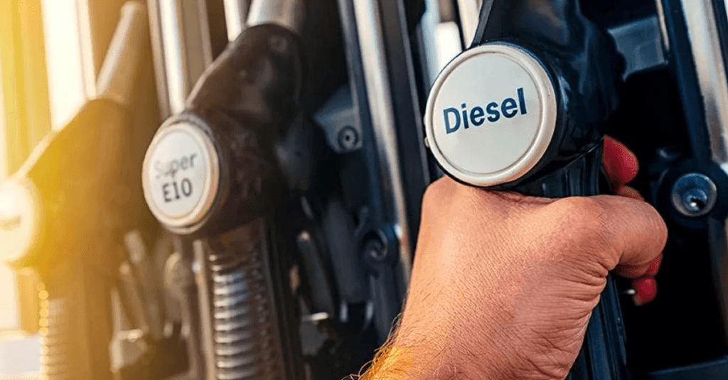 Hand holding a diesel fuel pump nozzle at a refueling station.