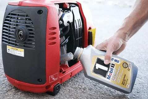 Pouring engine oil into a red portable generator during maintenance.