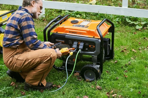 Man connecting appliances to a Generac 6500 watt generator outdoors