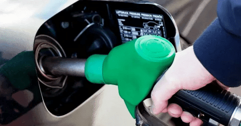 Green diesel fuel nozzle inserted into a vehicle fuel tank.