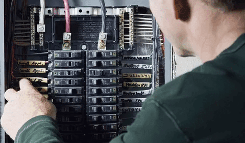 Technician checking circuit breaker panel to ensure safety and proper operation during testing
