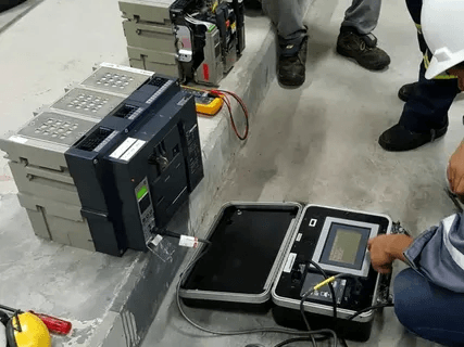Technician performing circuit breaker testing with analyzer in field conditions