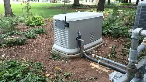 Outdoor standby generator installation with fuel line and wiring connections.