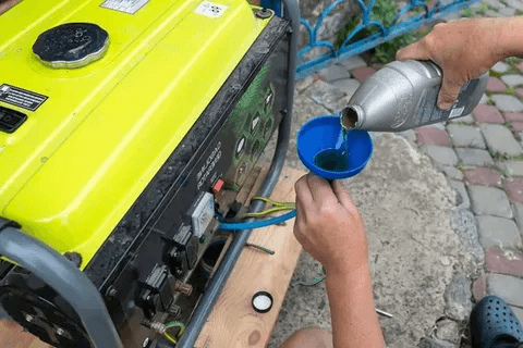 Pouring new oil into a yellow generator with a funnel.